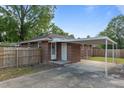 Rear view of a red brick house, fenced yard, and carport on a sunny day at 464 Camp Rd, Burlington, NC 27217