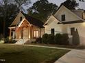 Stunning night view of a white home showcasing a wood-accented porch and well-lit landscaping at 512 Page St, Cary, NC 27511