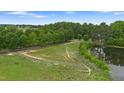 Scenic pasture with lush green grass, white fencing, mature trees, and a serene pond in the background at 5237 Christian Light Rd, Fuquay Varina, NC 27526
