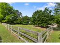 Expansive fenced pasture with vibrant green grass, mature trees, and a classic wooden fence at 5237 Christian Light Rd, Fuquay Varina, NC 27526