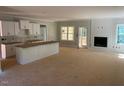Open-concept living space with fireplace, white kitchen cabinets, and unfinished floors at 539 Mulberry Rd, Spring Hope, NC 27882