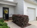 Close-up of townhome's front entrance with black door, white siding, and landscaped bushes at 80 Willow Green Dr, Clayton, NC 27527