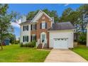 Charming two-story home with a brick facade, white siding, a well-manicured lawn and an attached garage at 805 Penncross Dr, Raleigh, NC 27610