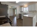 Well-lit kitchen with white cabinets, stainless steel appliances, and wood-look flooring, leading to a dining area at 805 Penncross Dr, Raleigh, NC 27610