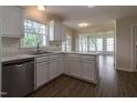 Bright kitchen featuring white cabinetry, stainless steel dishwasher, and durable wood-look flooring at 805 Penncross Dr, Raleigh, NC 27610