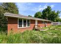 A cozy one-story brick house featuring large windows and a well-maintained roof, with a PODS container nearby at 995 Shawtown Rd, Lillington, NC 27546
