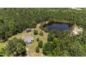 Aerial view of a home with a pond and outbuildings nestled in a wooded landscape at 1131 Pulley Gordon Rd, Zebulon, NC 27597