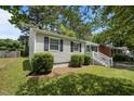 View of a charming single story home with lush landscaping, classic shutters, and a well-manicured lawn at 1208 W Murray Ave, Durham, NC 27704