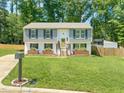 Split-level home with a well-manicured lawn, flower boxes, and wood fence at 1220 Sherbrooke Ct, Raleigh, NC 27612