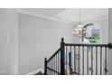 Open staircase featuring decorative iron railings, dark wood steps, and a modern chandelier at 1637 Dodford Ct, Wake Forest, NC 27587