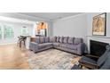 Open-concept living room with hardwood floors, a cozy fireplace, and modern gray sofa at 2242 Sweet Annie Way, Wake Forest, NC 27587