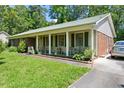 Side view of a single-story home featuring a brick facade, green shutters, and a well-kept lawn at 305 Reynolds N Ave, Durham, NC 27707