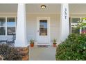 Close-up of charming front porch highlighting plants, decorative door, and stone accents on pillars, creating an inviting entry at 357 Sherrill Farm Dr, Benson, NC 27504