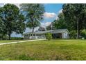 Ranch home with a covered porch, American flag, mature trees, and a circular driveway at 444 Barnette Rd, Louisburg, NC 27549