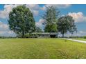 Ranch style home with a covered porch surrounded by mature trees and an American flag at 444 Barnette Rd, Louisburg, NC 27549