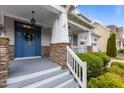 Charming front entrance with stone pillar accents, white railing, and a craftsman-style door with a wreath at 4562 Brighton Ridge Dr, Apex, NC 27539