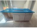 Newly installed kitchen island featuring white cabinets and a countertop covered in protective blue film at 6828 Galloway Dr, Middlesex, NC 27557
