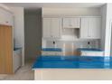 Bright kitchen featuring white cabinets, island and countertops covered in protective blue film at 6828 Galloway Dr, Middlesex, NC 27557