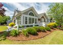 Charming gray home featuring attractive stone accents, manicured landscaping, and a white picket fence at 924 Carolina Bell Rd, Apex, NC 27502