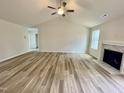 Light-filled living room with vaulted ceilings, ceiling fan, and wood-look floors with a fireplace at 158 Sourgum Ct, Zebulon, NC 27597