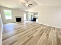 Bright living room with a fireplace, ceiling fan, and durable wood-look flooring at 158 Sourgum Ct, Zebulon, NC 27597