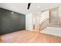 Spacious living room featuring hardwood floors, a modern accent wall, staircase, and abundant natural light at 2205 Tampa Ave, Durham, NC 27705