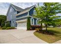 Side view of a blue house featuring an attached garage and lush landscaping at 2601 Brookstone Ridge, Raleigh, NC 27613