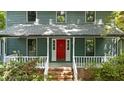 Inviting home featuring a bright red front door, covered porch, white railings and lush greenery at 522 Lochness Ln, Cary, NC 27511