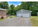 Detached two-car garage with white doors and light blue siding, nestled in a serene, wooded setting at 5652 Laurel Crest Dr, Durham, NC 27712