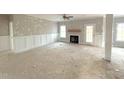 Bright living room with a fireplace, ceiling fan, wainscoting, and large windows, awaiting finishing touches at 7491 Sweetwater Dr, Nashville, NC 27856