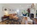 Sun-drenched living room with hardwood floors, a comfortable couch, fireplace, and doors to the backyard at 7804 Tylerton Dr, Raleigh, NC 27613