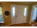 Bright entryway featuring a white front door with sidelights and natural light, complemented by a decorative mirror at 14 Striding Ridge Ct, Durham, NC 27713