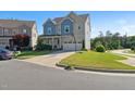 Charming two-story home with a two-car garage, blue accents, and a well-maintained front yard at 1600 Tinos Overlook Way, Apex, NC 27502