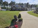Expansive lawn leads to a brick home with a three-car garage and a meticulously maintained, verdant landscape at 1655 Kingfisher Ct, Nashville, NC 27856