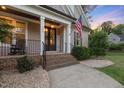 Inviting front porch with brick steps, decorative plants, rocking chairs, and an American flag at 175 Lockamy Ln, Youngsville, NC 27596
