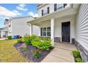 Inviting front porch adorned with stone accents, landscaping, and a black front door at 200 Chateau Way, Angier, NC 27501