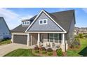 Charming home featuring a covered front porch with chairs, a manicured lawn, and a two car garage at 2096 Dowell Ct, Burlington, NC 27215
