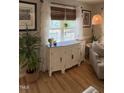 Close up of sideboard with decor, windows and hardwood floors in a neutrally decorated living room at 50 Peggy Ct, Raleigh, NC 27603