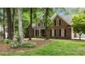 Charming brick home with inviting front porch and manicured lawn, framed by mature trees and colorful flowers at 5916 Two Pines Trl, Wake Forest, NC 27587