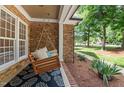 Inviting covered front porch features a porch swing, brick accents, and patterned rug for outdoor relaxation at 5916 Two Pines Trl, Wake Forest, NC 27587