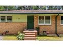 Close-up of unit 725 featuring brick steps, a green security door, and well-maintained landscaping at 725-727 Locust Ln, Raleigh, NC 27603