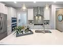 Well-appointed kitchen features a stainless steel range hood, gray backsplash, and a spacious quartz countertop island at 87 Addison Pond Ct, Zebulon, NC 27597