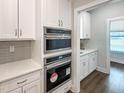 Modern kitchen includes built-in stainless steel microwave and oven appliances and white cabinets and countertops at 87 Addison Pond Ct, Zebulon, NC 27597