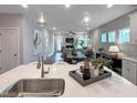 Open-concept living and dining area showcases modern lighting and seamless flow from kitchen to living spaces at 87 Addison Pond Ct, Zebulon, NC 27597