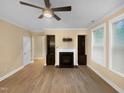 Bright living room featuring a fireplace with built-in shelving, a modern ceiling fan, and sleek hardwood floors at 8844 Forester Ln, Apex, NC 27539