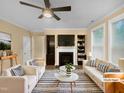 Bright, staged living room featuring a fireplace with built-in shelving, neutral furniture, and modern ceiling fan at 8844 Forester Ln, Apex, NC 27539