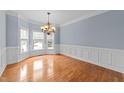 Dining room featuring hardwood floors, wainscoting, bay window and an elegant chandelier at 12217 Beestone Ln, Raleigh, NC 27614