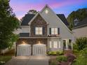 Elegant home featuring stone accents, a two-car garage, and warm exterior lighting at dusk at 12217 Beestone Ln, Raleigh, NC 27614