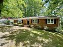 Traditional brick ranch home with a well manicured front yard and a black front door at 1713 S Garnett St, Henderson, NC 27536