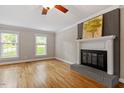 Cozy living room with hardwood floors, a brick fireplace, and natural light from two windows at 2300 Cowden Ct, Raleigh, NC 27612